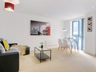 Spacious living area with modern decor, featuring a dining table set for four, a large window, and a monochrome cityscape wall art